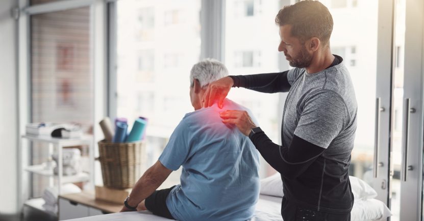 Physiotherapy, shoulder pain and man with senior patient for orthopedic care, consulting and wellness. Chiropractor, health and physical therapist with person for rehabilitation, support and healing.